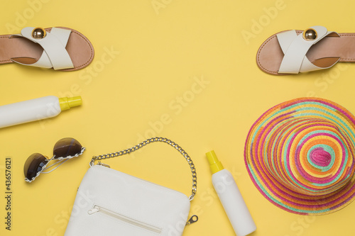 Bag, sandals, glasses and sunscreen on a yellow background. Space for the text. Flat lay.