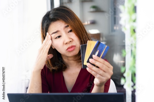 sad Asian woman having problem with debt ,over spending money from shopping hand holding credit card and worry about late , deadline payment