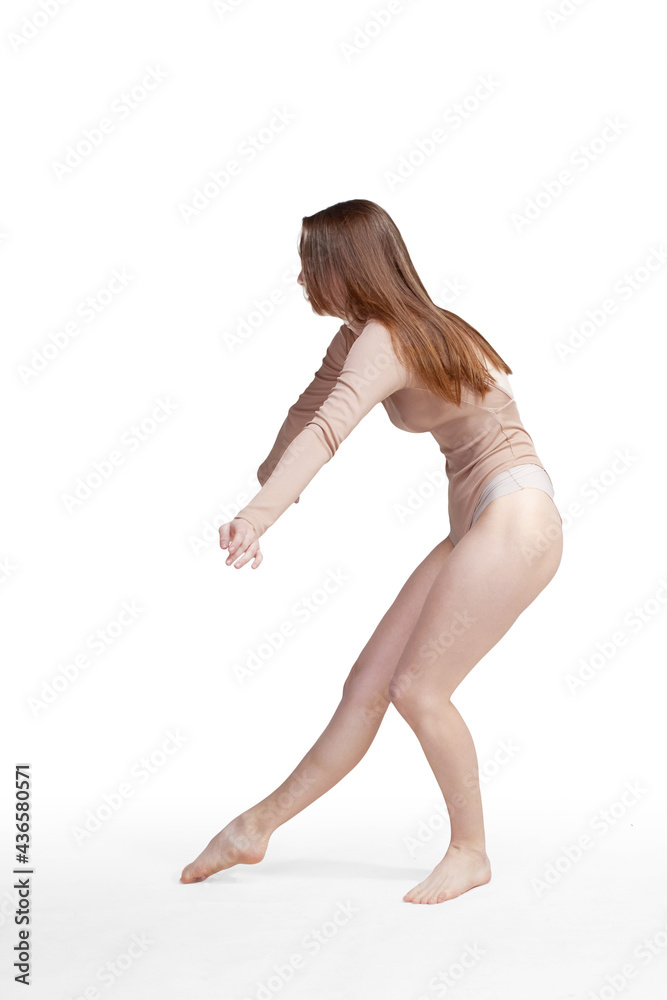 Young slender girl, with long hair, in a beige bodysuit, in the studio on a white background, practicing gymnastics Young slender girl, with long hair, in a beige bodysuit, in the studio on a white background, practicing gymnastics