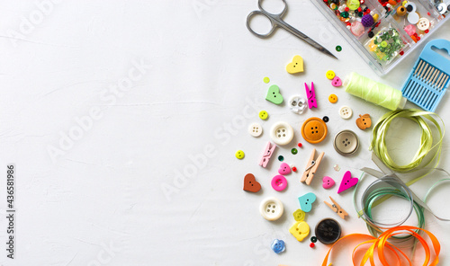 Set for needlework- colorful buttons, ribbons, scissors and neebles on white background.