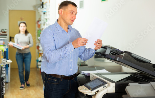 Confident businessman using printer in office. High quality photo