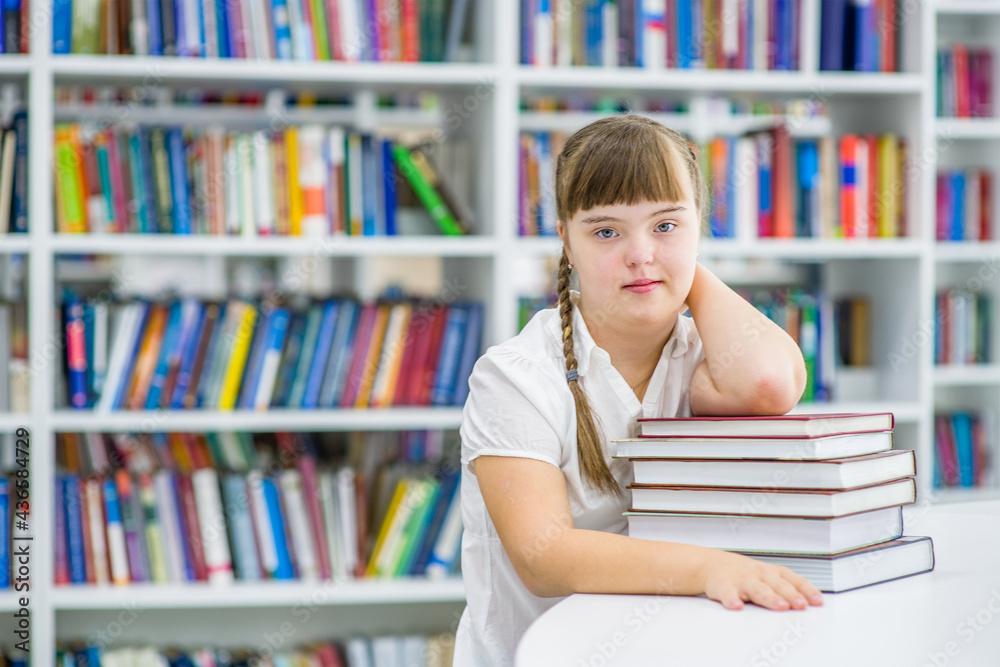 Young girl with syndrome down at library. Education for disabled children concept. Empty space for text Young girl with syndrome down at library. Education for disabled children concept. Empty space for text