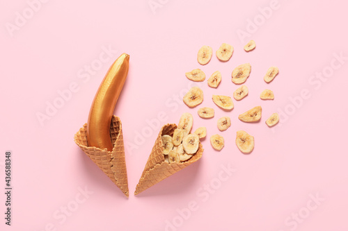 Creative composition with painted banana and waffle cones on color background
