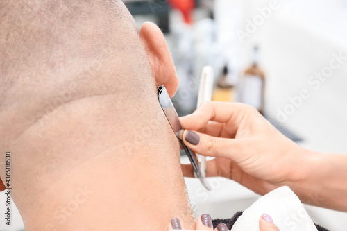 Female hairdresser shaving client in beauty salon, closeup