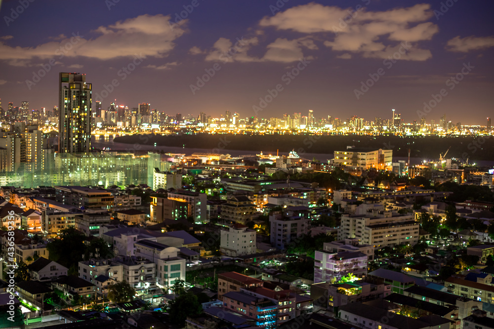 Obraz premium The high angle background of the city view with the secret light of the evening, blurring of night lights, showing the distribution of condominiums, dense homes in the capital community