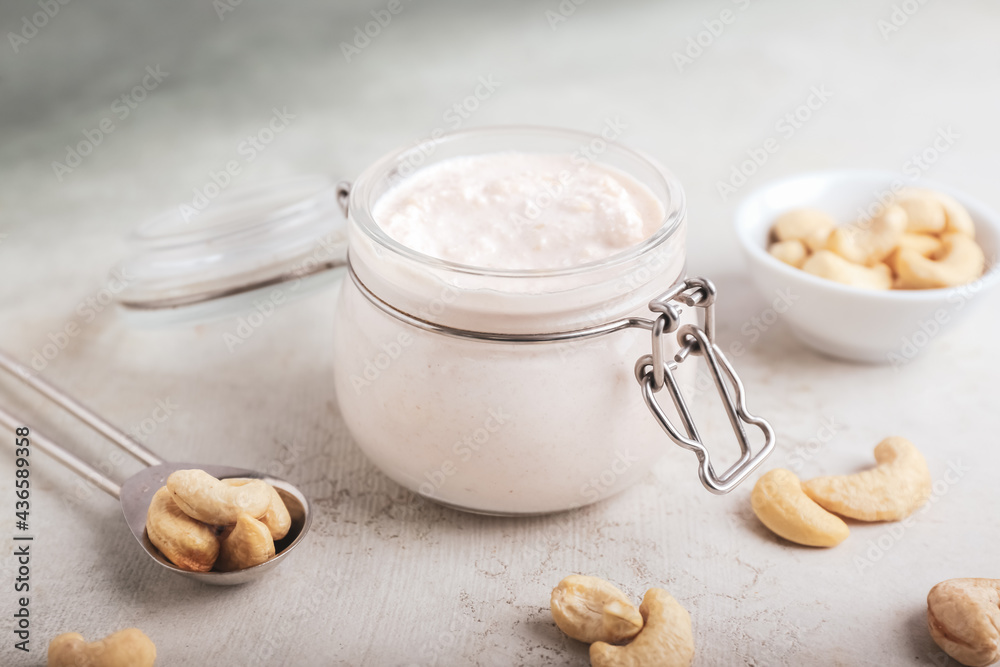 Jar with cashew sour cream and nuts on light background, closeup Jar with cashew sour cream and nuts on light background, closeup