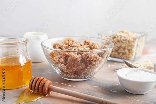 Bowl of natural scrub and ingredients on light background