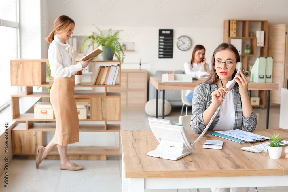 Female accountant talking by phone in office Female accountant talking by phone in office