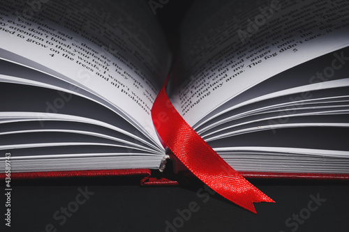 Open book with bookmark on dark background, closeup