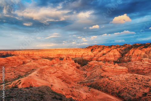 The view from the top to the canyon  sunset sky  erosion  plateau  cloudy sky and mountains on the horizon. Red rocks and layers. Panorama of the Charyn canyon in Kazakhstan.