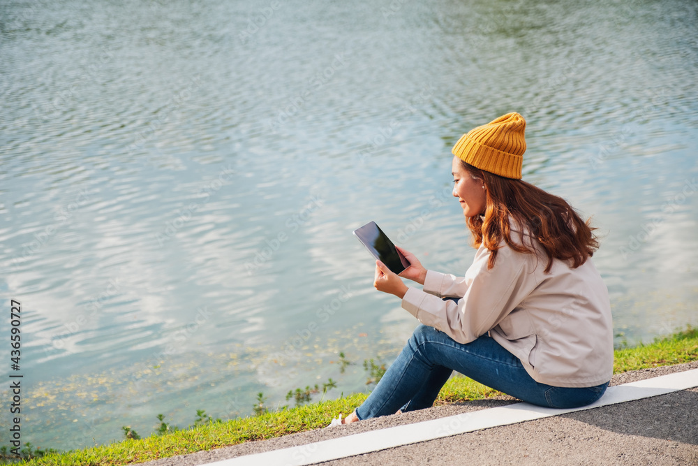 A young woman holding and using digital tablet while traveling mountains and lake