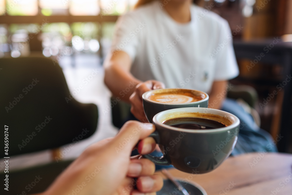 Closeup image of a man and a woman clinking coffee mugs in cafe Closeup image of a man and a woman clinking coffee mugs in cafe