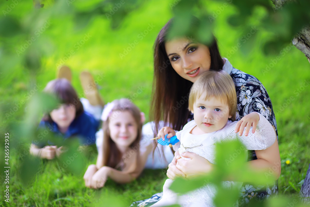 Young large family on a summer morning walk. Beautiful mother with children is playing in the park. Young large family on a summer morning walk. Beautiful mother with children is playing in the park.
