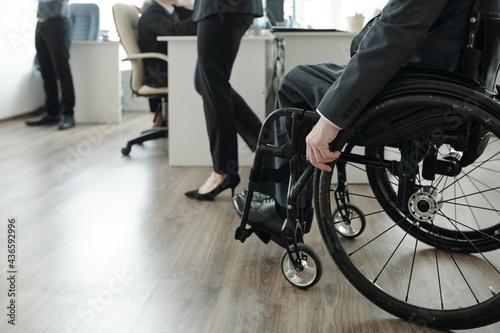 Handicapped businessman in formalwear moving along open space office © pressmaster