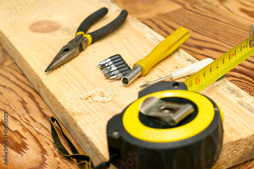 measuring tape pliers pencil screwdrivers and a board on the carpenter's workbench