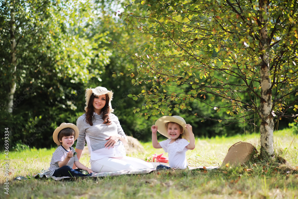 Happy family with children having picnic in park, parents with kids sitting on garden grass and eating watermelon outdoors Happy family with children having picnic in park, parents with kids sitting on garden grass and eating watermelon outdoors