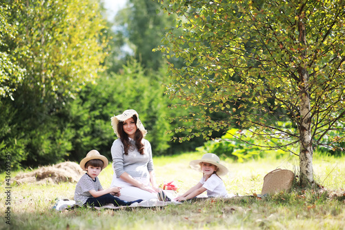 Fototapeta Naklejka Na Ścianę i Meble -  Happy family with children having picnic in park, parents with kids sitting on garden grass and eating watermelon outdoors