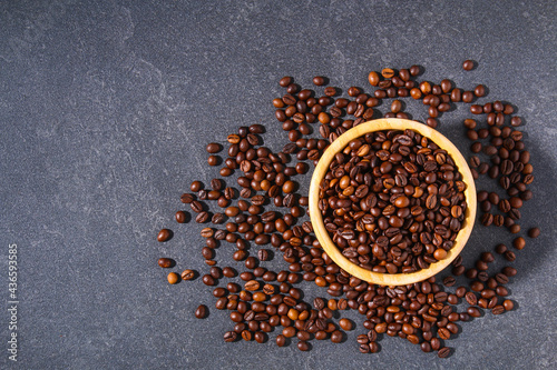 Roasted brown coffee beans on a gray background. Coffee beans in wooden bowls. Top view. © detry26