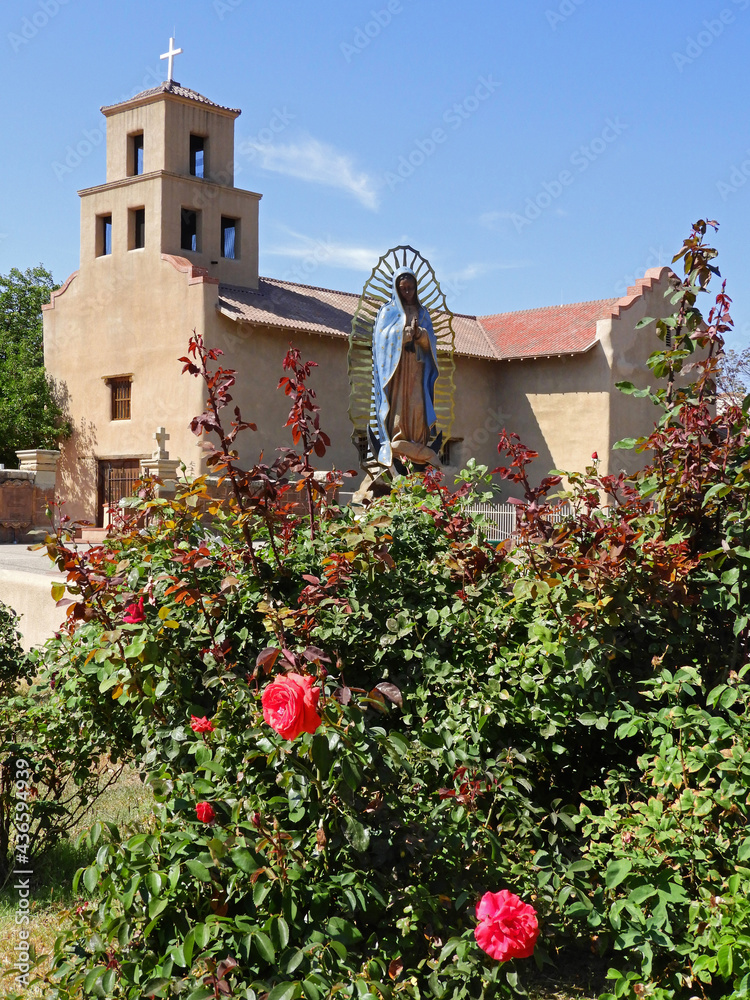 the exterior of the historic church of our lady of guadalupe and red roses  in santa fe, new mexico