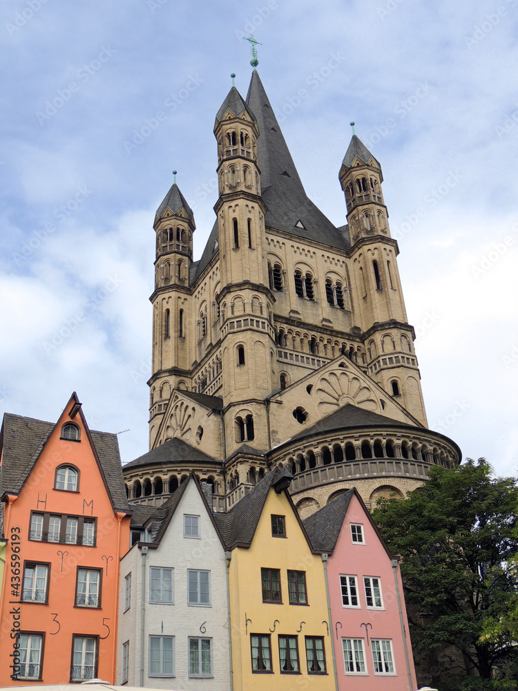 great st. martin church looms above the  colorful buildings on the riverfront  of  old town  cologne, germany     