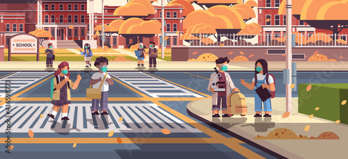 mix race schoolchildren in masks crossing road on crosswalk pupils walking to school coronavirus pandemic concept