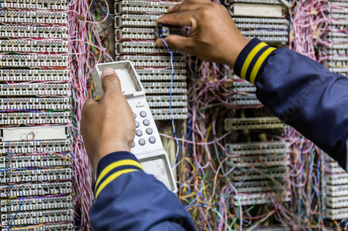 Technician checks and repairs the telephone line in PBX cabinet photo