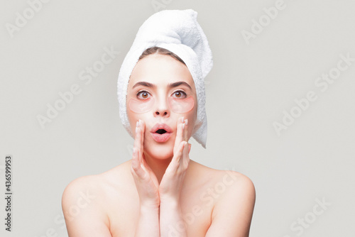 Amazed woman applying eye patches. Close up portrait girl with towel on head. Portrait of beauty woman with eye patches showing an effect of perfect skin. Eyes mask cosmetic patches woman face closeup