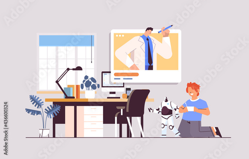 schoolboy playing with radio controlled robotic toy and discussing with teacher during video call self isolation