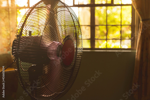 A running electric fan inside a room during a sweltering and hot day. Concept of heat wave or summer weather.