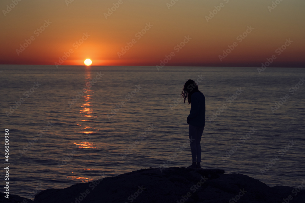sunset in the mountains by the sea and a female silhouette on the beach