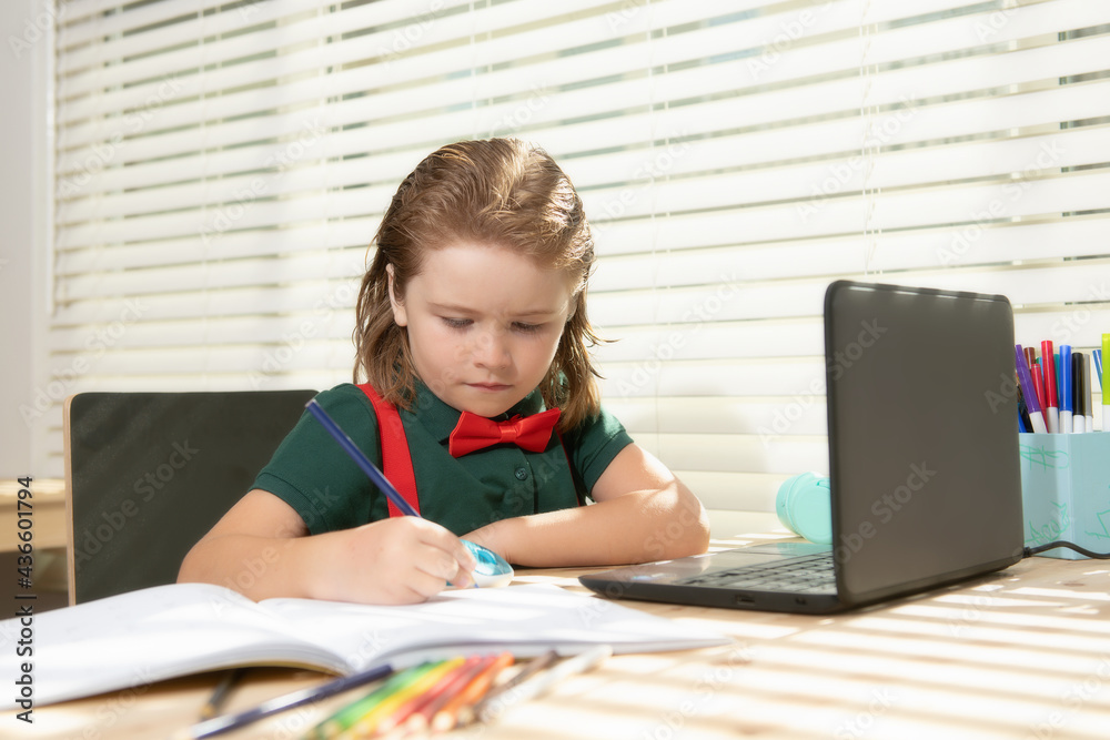 Smart school boy does homework in school class. Writes text from laptop notebook. Smart school boy does homework in school class. Writes text from laptop notebook.