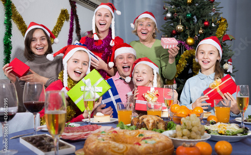 Family with children sitting with presents at Christmas dinner. High quality photo