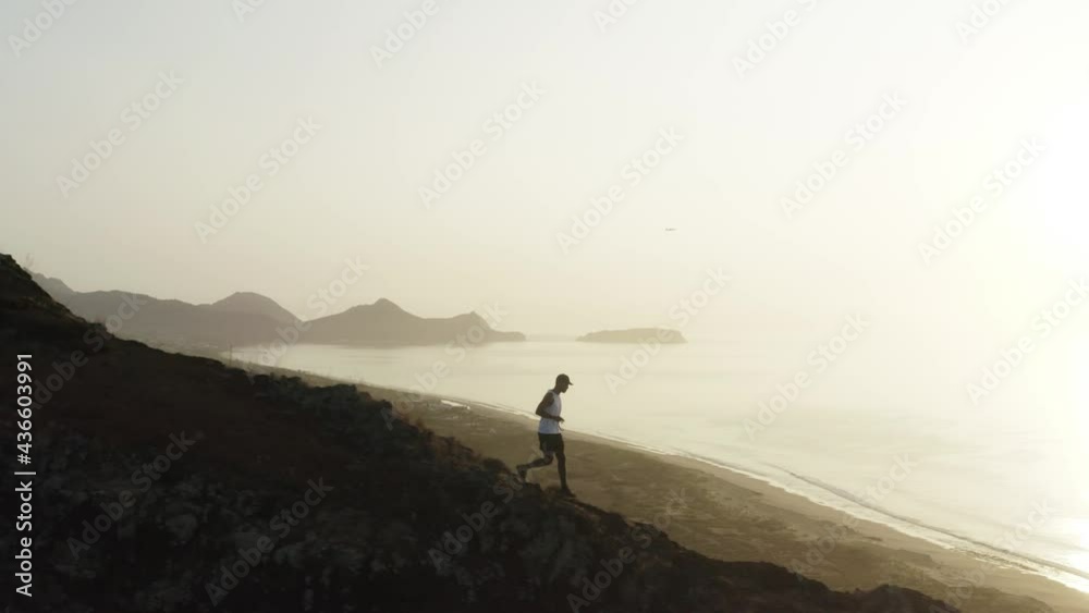 Tracking guy running down slope of mountain ridge with bright sunrise Tracking guy running down slope of mountain ridge with bright sunrise