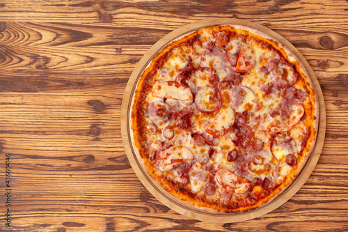 Top view of freshly baked pizza on wooden background