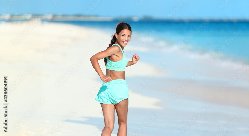 Happy running fitness girl looking back smiling on beach run jogging active healthy lifestyle. Asian woman athlete exercising cardio working out in summer outdoors. Happy running fitness girl looking back smiling on beach run jogging active healthy lifestyle. Asian woman athlete exercising cardio working out in summer outdoors.