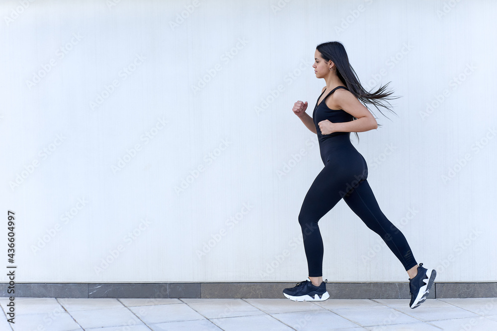 Young woman with fit body running in sportswear