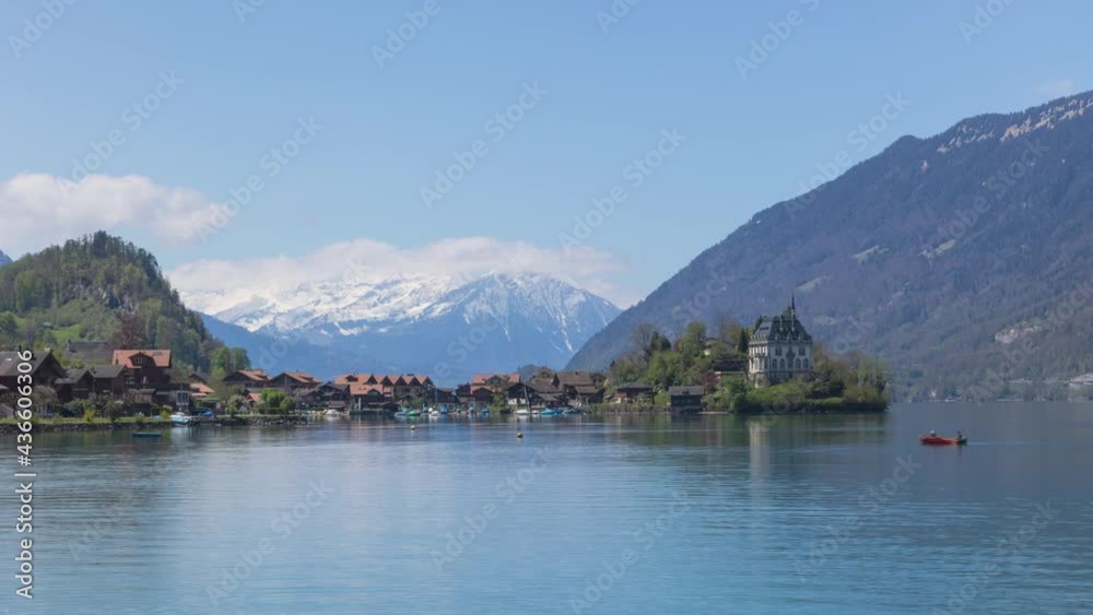 Timelapse View of the peninsula and former castle with snowy mountains on the background. Iseltwald, Lake Brienz, Canton Bern, Switzerland. Timelapse View of the peninsula and former castle with snowy mountains on the background. Iseltwald, Lake Brienz, Canton Bern, Switzerland.