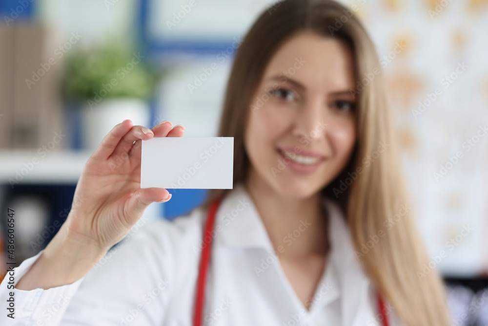 Smiling female doctor holding white business card Smiling female doctor holding white business card