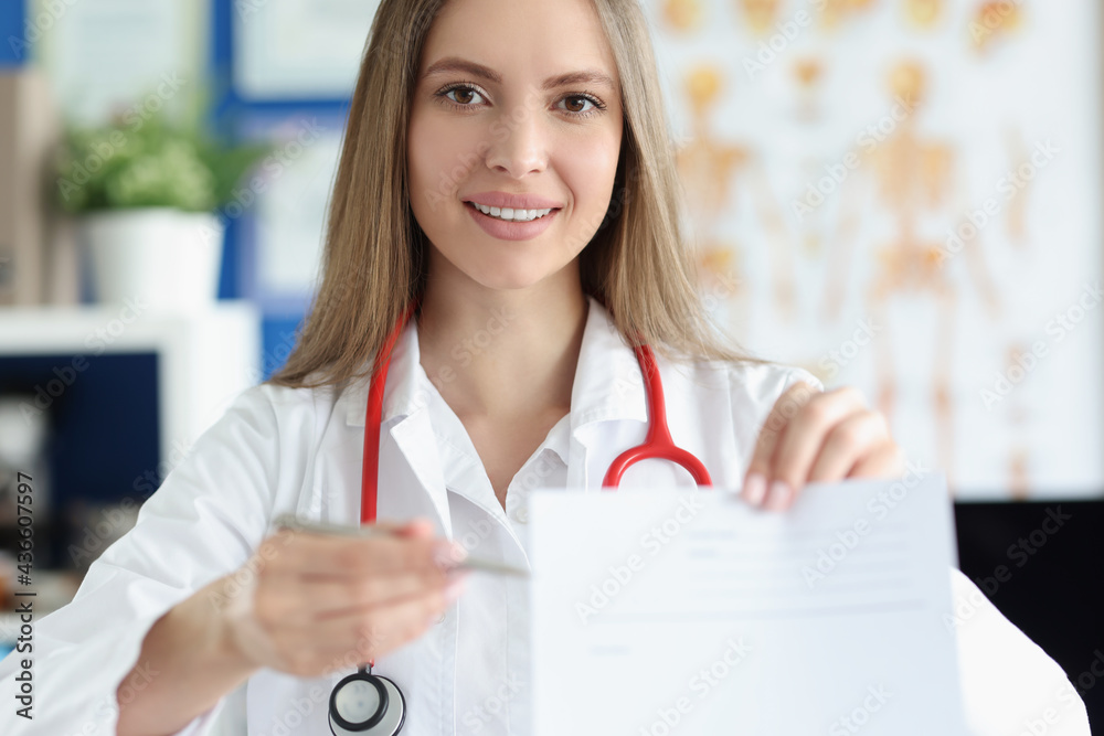 Smiling female doctor holding prescription blank for medicines Smiling female doctor holding prescription blank for medicines