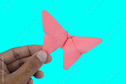 Pink butterfly made with small craft paper and nicely placed on a paper background on hand