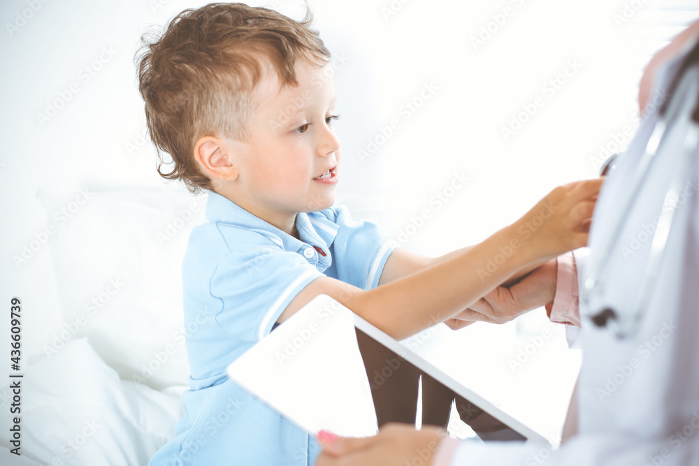 Happy smiling male kid-patient at usual medical inspection. Doctor and young boy in the clinic. Medicine concepts Happy smiling male kid-patient at usual medical inspection. Doctor and young boy in the clinic. Medicine concepts