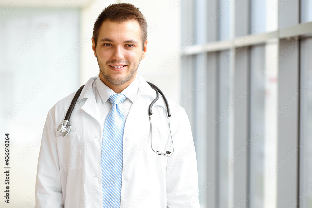 Male dark hair doctor standing in the modern clinic. Perfect medical service in the hospital. Medicine concept Male dark hair doctor standing in the modern clinic. Perfect medical service in the hospital. Medicine concept