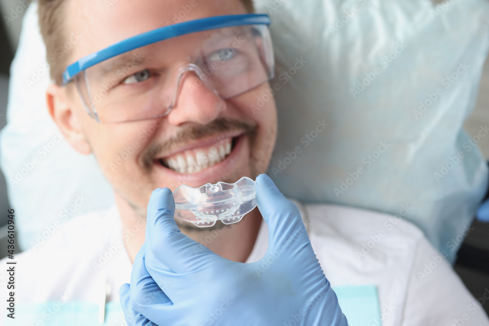 © H_Ko - Dentist tries on transparent mouthguard to correct bite and bruxism problems © H_Ko - Dentist tries on transparent mouthguard to correct bite and bruxism problems