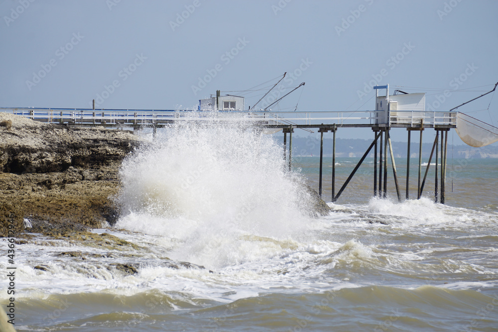 wave breaking on the beach against the old wood fisherman hut in Vendée, france