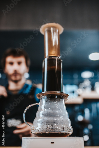 Pressurized coffee brewing using an aeropress - the barista presses the piston photo
