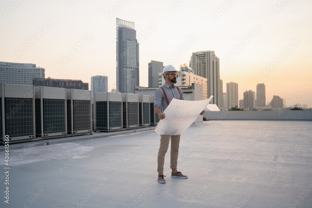 Engineer with blueprints on the roof of a building Engineer with blueprints on the roof of a building
