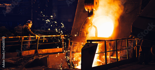 Molten metal pouring from blast furnace in foundry. Iron casting process in steel mill, metallurgical plant, heavy industry.