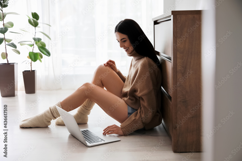 Woman with laptop sitting on warm floor at home. Heating system Woman with laptop sitting on warm floor at home. Heating system