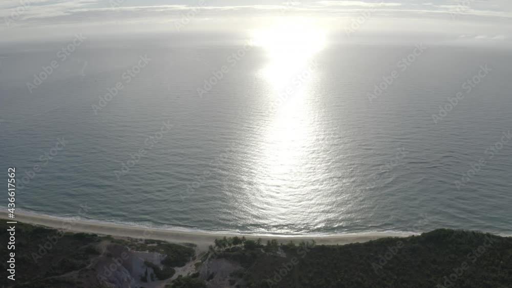 Vue de drone de droite à gauche de l'océan, marée basse. Falaises, couché de soleil. Été à Praia Pitinga, Bahia, Brésil. Paysage tropical avec palmiers, forêt, sable, eau; soleil 