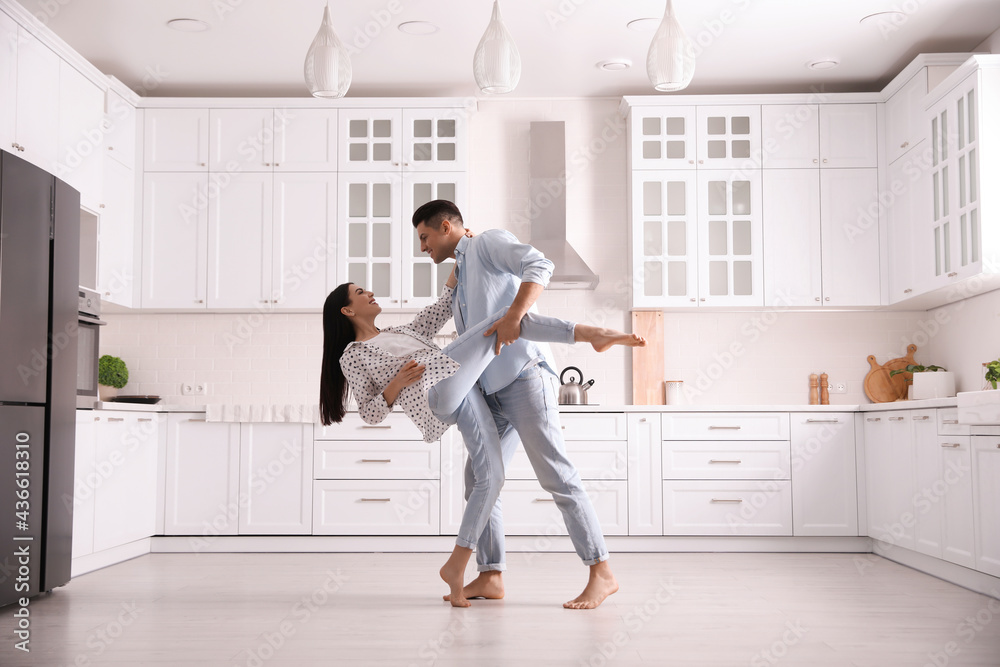 Happy couple dancing barefoot in kitchen. Floor heating system Happy couple dancing barefoot in kitchen. Floor heating system